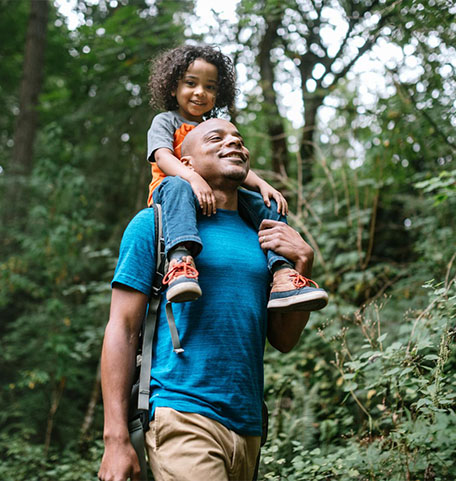 Man with his child on his shoulders in a forest